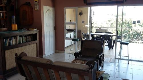 a living room with a chair and a table and windows at Serendipity Country House in Amanzimtoti