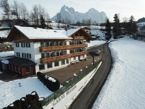 un grand bâtiment dans la neige recouvert de neige dans l'établissement Garni Hotel Melissa, à Castelrotto