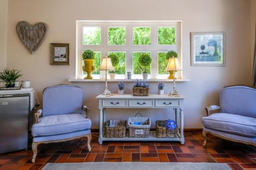 two chairs and a table in a room with two windows at Oude Berg Guesthouse - 10 Caledon Street in George