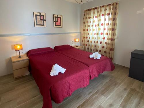 a bedroom with a red bed with towels on it at Mda Playa del Cantal in Mojácar