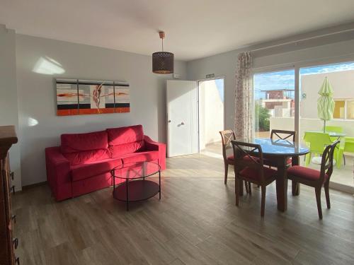 a living room with a red couch and a table at Mda Playa del Cantal in Mojácar