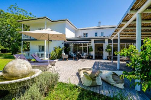 a house with a patio with chairs and an umbrella at Oude Berg Guesthouse - 10 Caledon Street in George