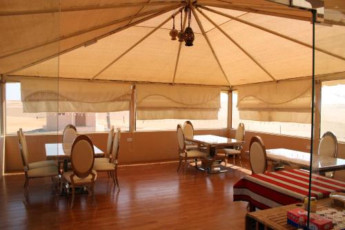 une salle à manger avec des tables et des chaises dans une tente dans l'établissement Safari Dunes Camp, à Ḩawīyah