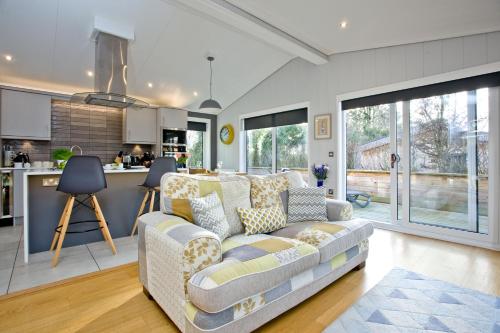 a living room with a couch and a kitchen at Nyland Lodge - Hot Tub - Fireplace - Free Parking & WiFi in Cheddar