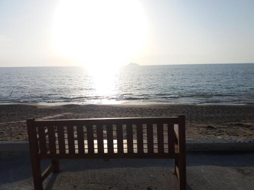a bench sitting on the beach looking at the ocean at GARDEN HOUSE, Kalamaki in Tympáki