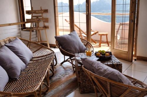 a room with wicker chairs and a table with a bowl of fruit at Boscha Villas 102 in Bandung