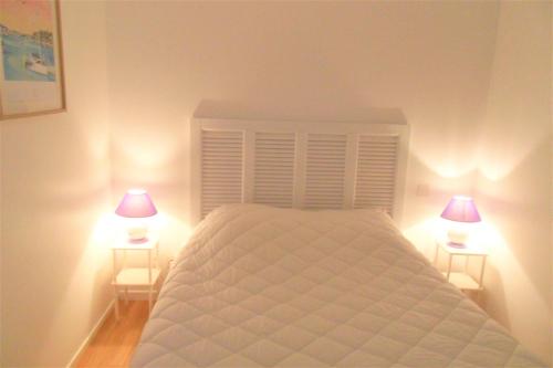Guidel-PlageにあるApt 6 pers - Magnifique vue mer - Belle terrasse - AZILIZのベッドルーム1室(白いベッド1台、ランプ2つ付)