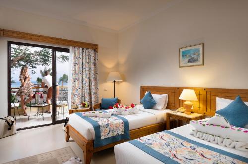 a hotel room with two beds and a balcony at Three Corners Fayrouz Plaza Beach Resort in Port Ghalib