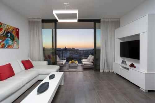 a living room with a white couch and a tv at Garnet by HolyGuest in Tel Aviv