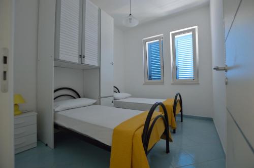 a white bedroom with a bed and two chairs at Holiday Apartments Azzurro Salento in Torre Vado