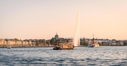 a boat in the water with a fountain at Swiss Luxury Apartments Geneva in Geneva
