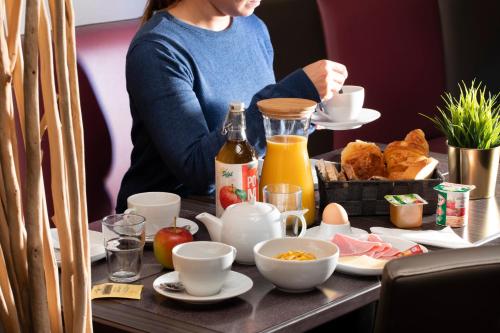 a woman sitting at a table with breakfast food at Elysées Hôtel in Paris