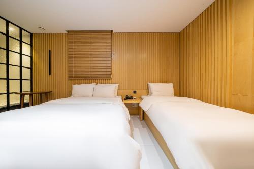 two beds in a small room with yellow walls at Hotel The Designers Kondae in Seoul