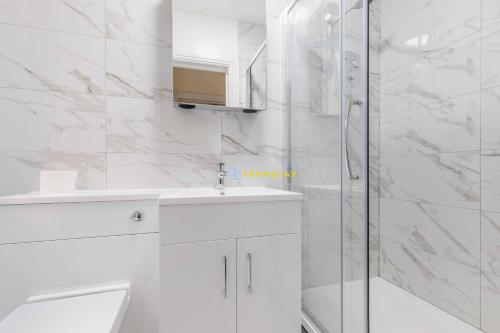 a white bathroom with a shower and a sink at 2 BED Modern apartment. Close to station & PARKING in Slough