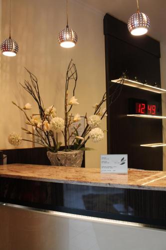 a counter with a clock and a vase of flowers at City Hotel Mercator in Frankfurt/Main