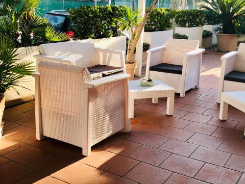a group of wicker chairs and tables on a patio at Hotel Garisenda B&B - in Centro a Riccione - in Riccione