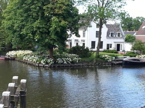 a house next to a river with a boat at 'Room Eleven' aan de Vecht in Vreeland