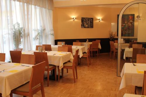 a dining room with tables and chairs with white tablecloths at City Hotel Mercator in Frankfurt/Main