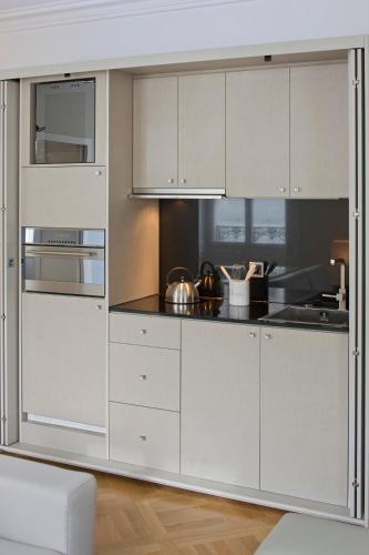 a kitchen with white cabinets and stainless steel appliances at Swiss Luxury Apartments Geneva in Geneva
