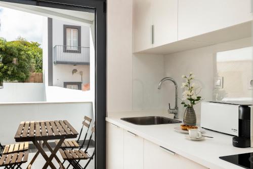 a kitchen with white cabinets and a sink and a window at Belem Design Apartments by Homing in Lisbon