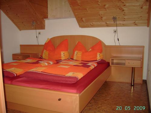 ein Bett mit einer orangefarbenen Bettdecke und Kissen darauf in der Unterkunft Ferienwohnung A 55 m2 in Lachtal