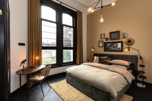 Goirle的住宿－Stella Suites Boutique Hotel，一间卧室配有一张床、一张书桌和一个窗户。