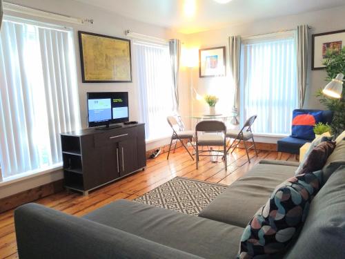 a living room with a couch and a tv and a table at Perfect Central City Location - Parking - 4 Beds - 2 Bedrooms in Belfast