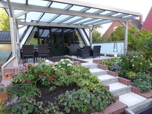 a patio with a pergola with chairs and flowers at Ferienhaus Hubertus, 95059 in Rhauderfehn