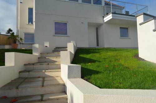 a white house with stairs and green grass at Skysail in Mevagissey
