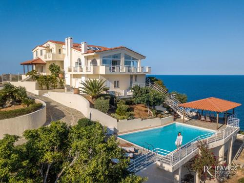 a house with a swimming pool in front of the ocean at Andromeda in Agia Pelagia