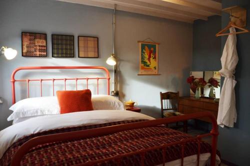 a bedroom with a bed with an orange pillow at Grain Store Cottage in Narberth