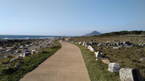 a person walking down a path next to the ocean at Casas dos Seixos in Moledo