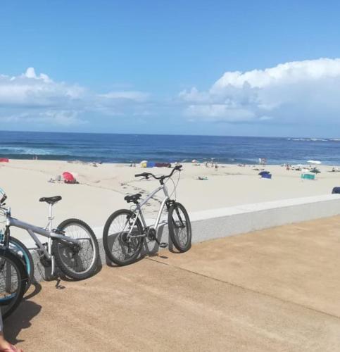 two bikes parked next to a beach with the ocean at Casas dos Seixos in Moledo