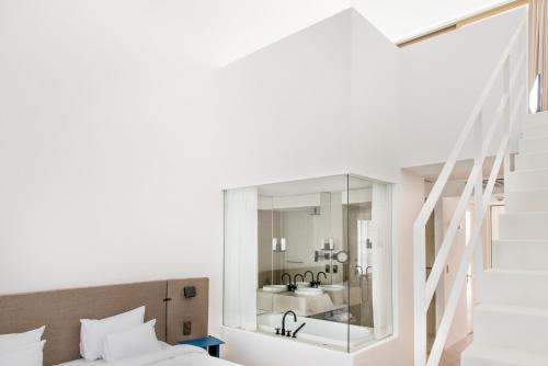 a bedroom with a bed and a bathroom with a mirror at Hôtel de Tourrel, Saint Rémy de Provence, a Member of Design Hotels in Saint-Rémy-de-Provence