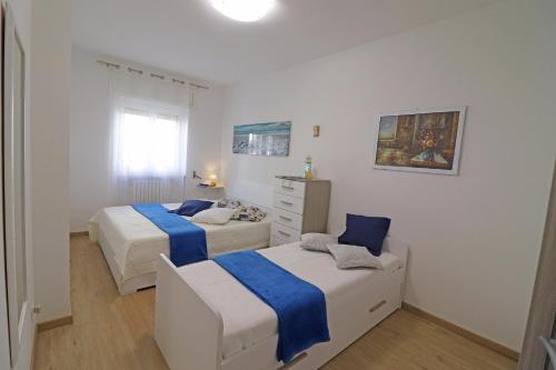 2 Betten in einem weißen Zimmer mit blauer Bettwäsche in der Unterkunft Holiday Apartment With Wi-fi, Air Conditioning And Balcony; Pets Allowed in Otranto