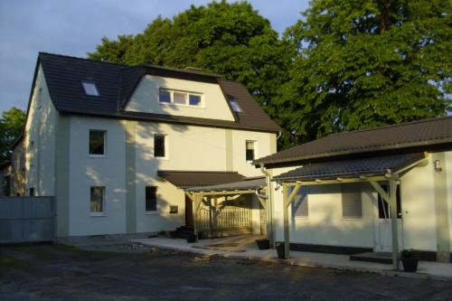 ein weißes Haus mit einem schwarzen Dach und einer Garage in der Unterkunft Ferienwohnungsvermietung Leitel in Brandenburg an der Havel