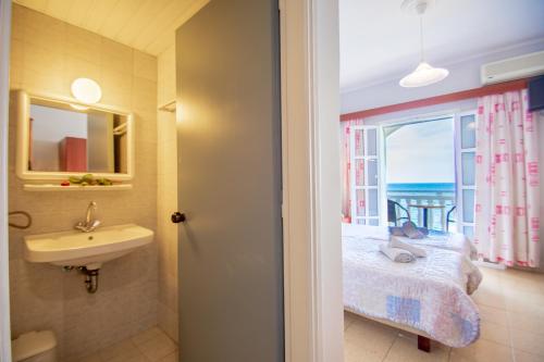 Agoulos Beach Hotel في أرغاسي: حمام مع حوض وسرير ونافذة