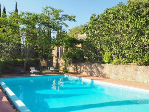a large blue swimming pool with a stone wall at Il Fico in Chianti in Gaiole in Chianti