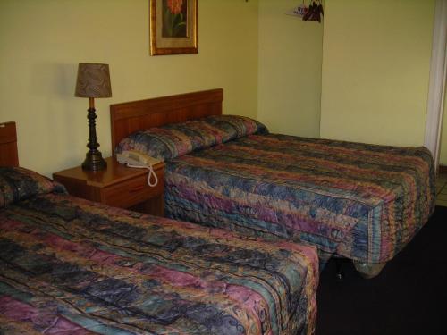 a hotel room with two beds and a lamp at Hollywood Motel in Kenova