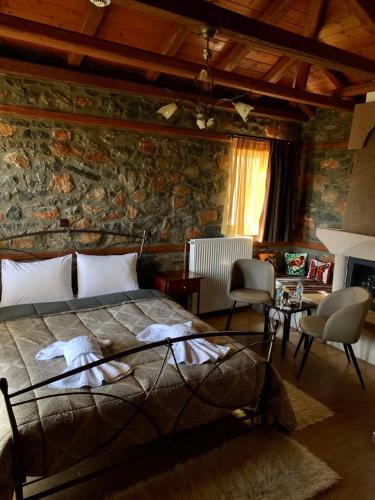 a bedroom with a bed and a stone wall at Guesthouse Nifada tou Vorra in Palaios Agios Athanasios