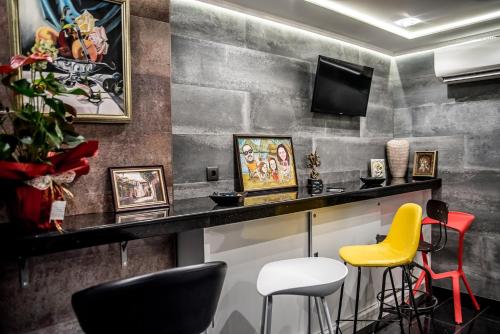 a bar with yellow and black chairs and a television at Boutique Guest house 7th Sense in Plovdiv