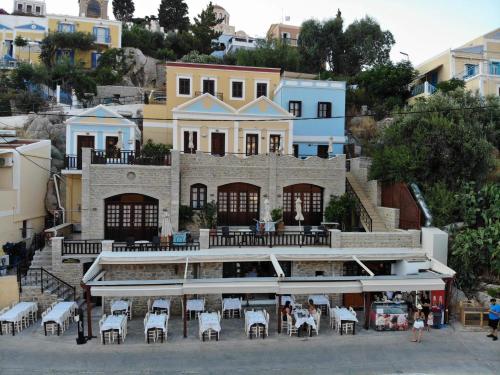 a building with tables and chairs in front of it at Odyssia in Symi