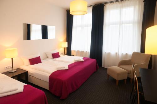 a hotel room with two beds and a chair at Goldmarie in Berlin
