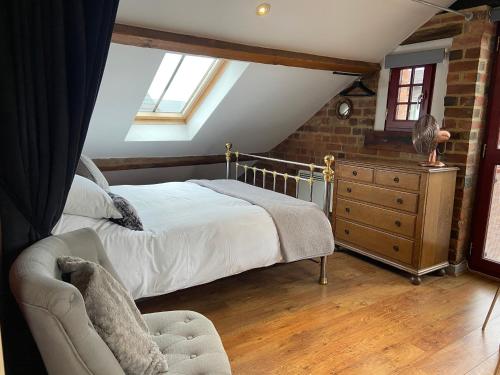 a bedroom with a bed and a chair and a dresser at Victorian Penthouse Apartment in Gloucester