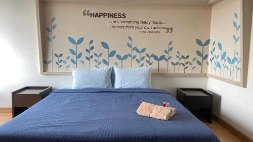 a bed with a blue comforter and two night stands at Teddy@Thammasart in Pathum Thani