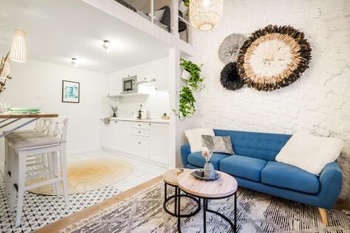 ブダペストにあるROOMLI Boho Chic Apartmentsの青いソファとキッチンのあるリビングルーム
