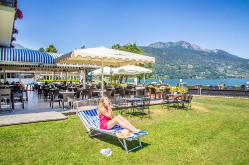 a woman sitting on a bench next to the water at Garnì Bellavista in Calceranica al Lago