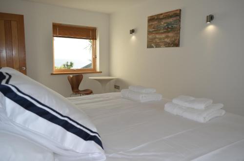 a bedroom with a white bed with towels on it at Skysail in Mevagissey