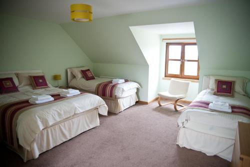 Habitación con 2 camas y una silla. en Bamflatt Farm Bed & Breakfast en Strathaven