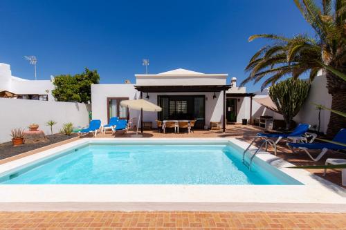 a swimming pool in front of a house at Villas Reina in Costa Teguise
